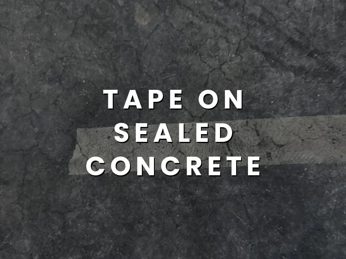 Tape on sealed concrete: a strip of sealer and color lifted from a dark stained concrete floor where painter's tape had been applied