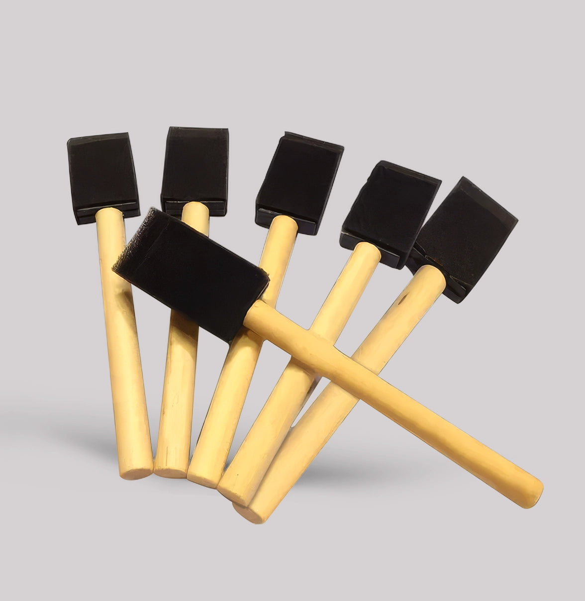 Set of six small sponges with black foam heads and yellow handles on a gray background
