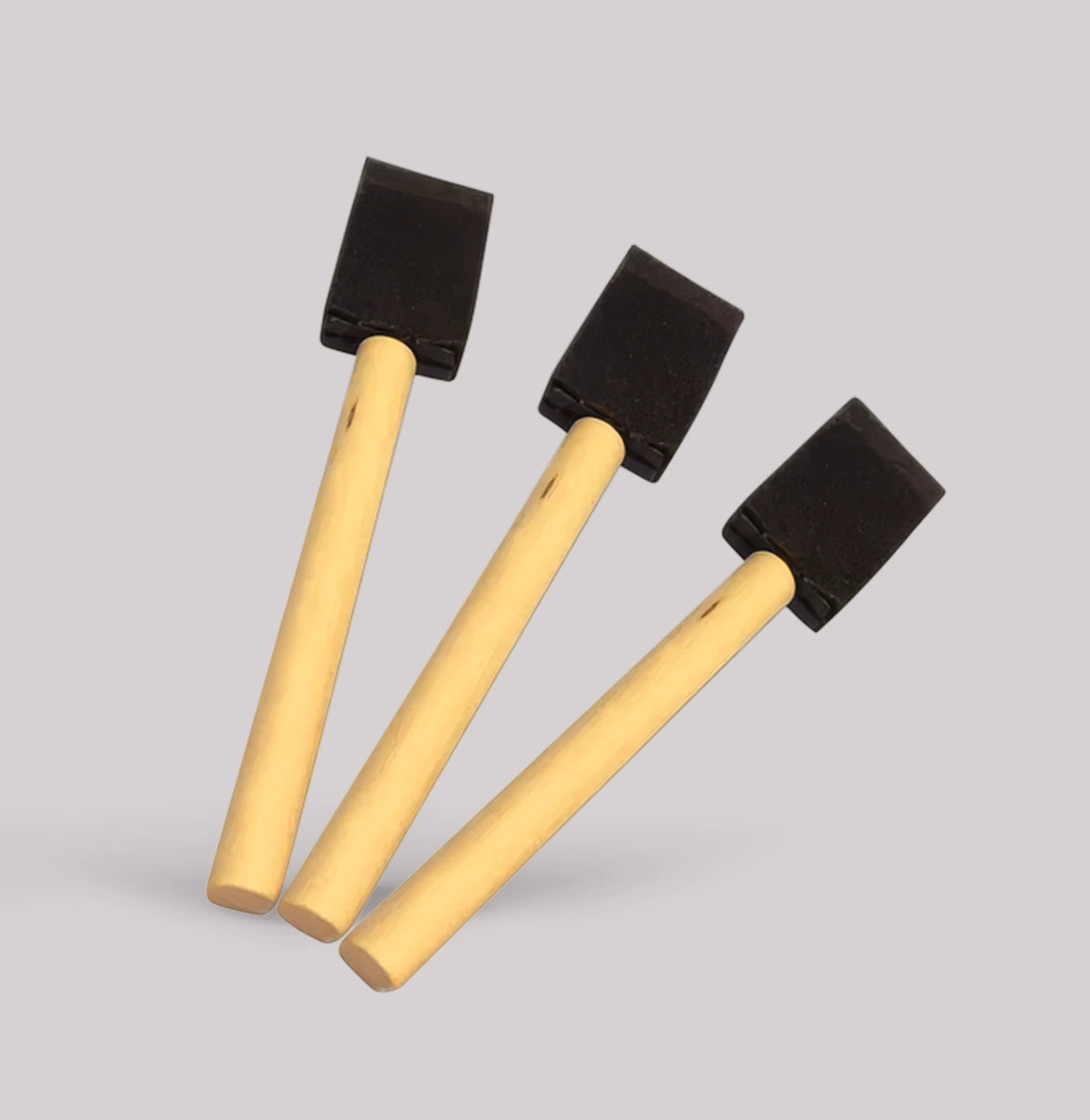 Three sponges with black foam heads and wooden handles on a gray background
