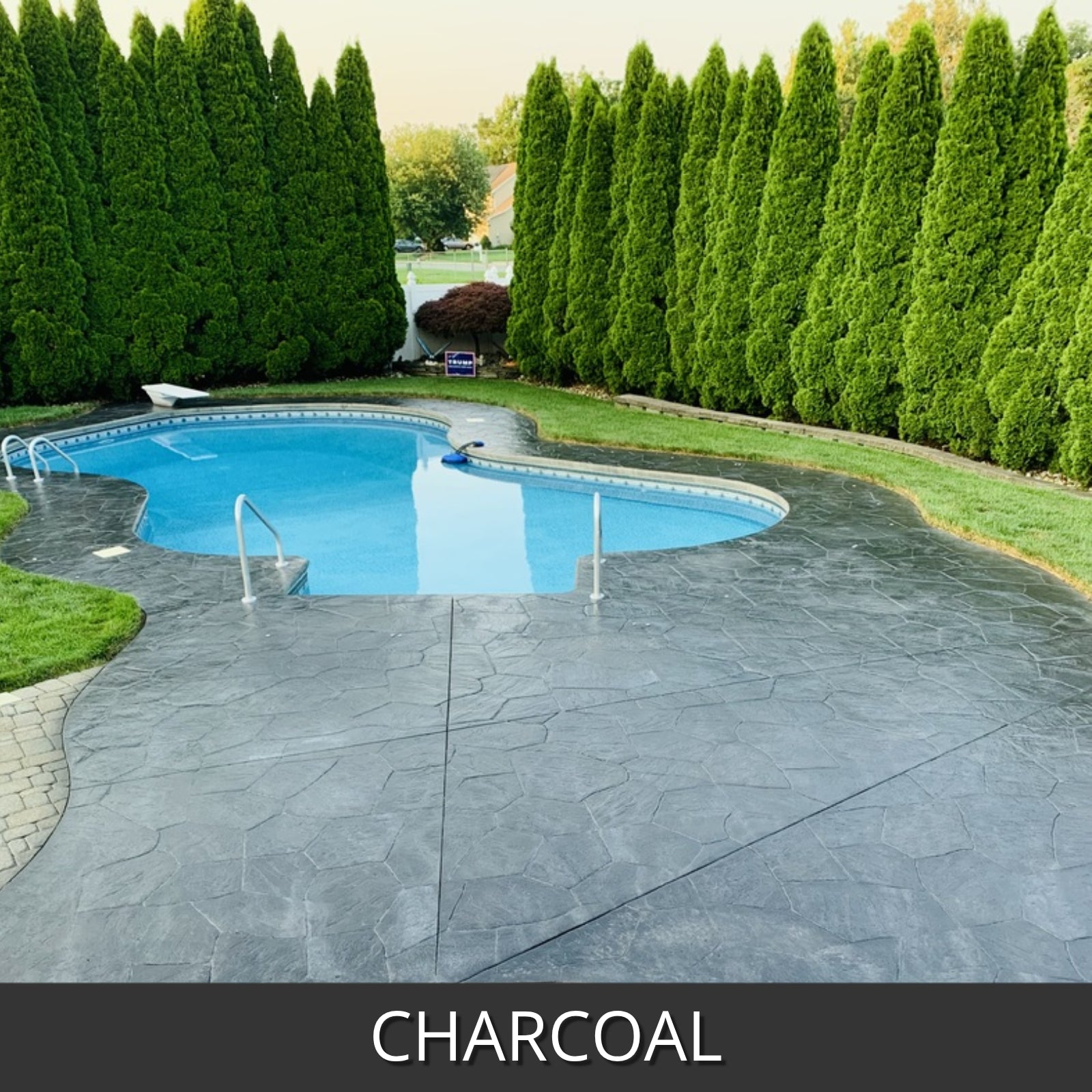 Pool area with antiquing charcoal-colored concrete patio and greenery