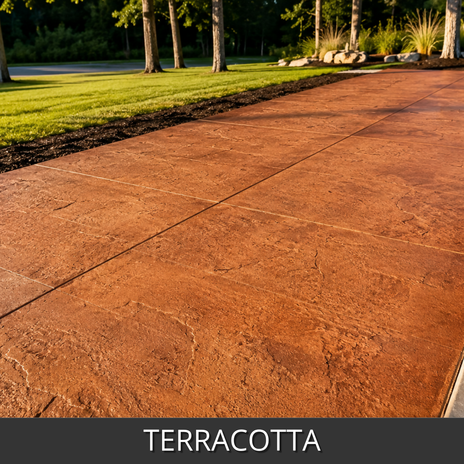 Terracotta-colored stamped concrete pavers shown outdoors on a driveway or walkway, with grass, trees, and landscaping in the background