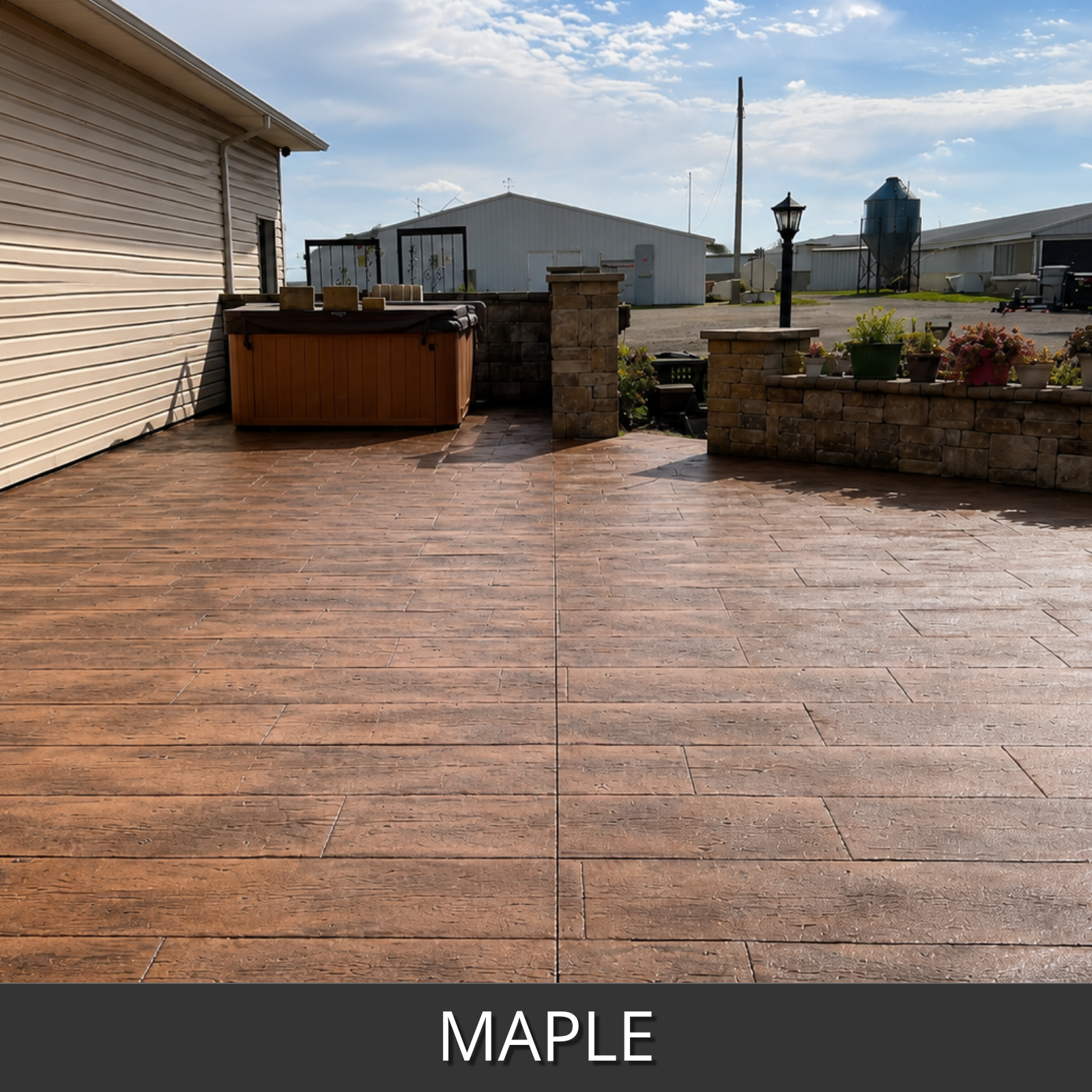 A large outdoor patio area with wood-look rectangular pavers in maple color, shown installed in front of a house