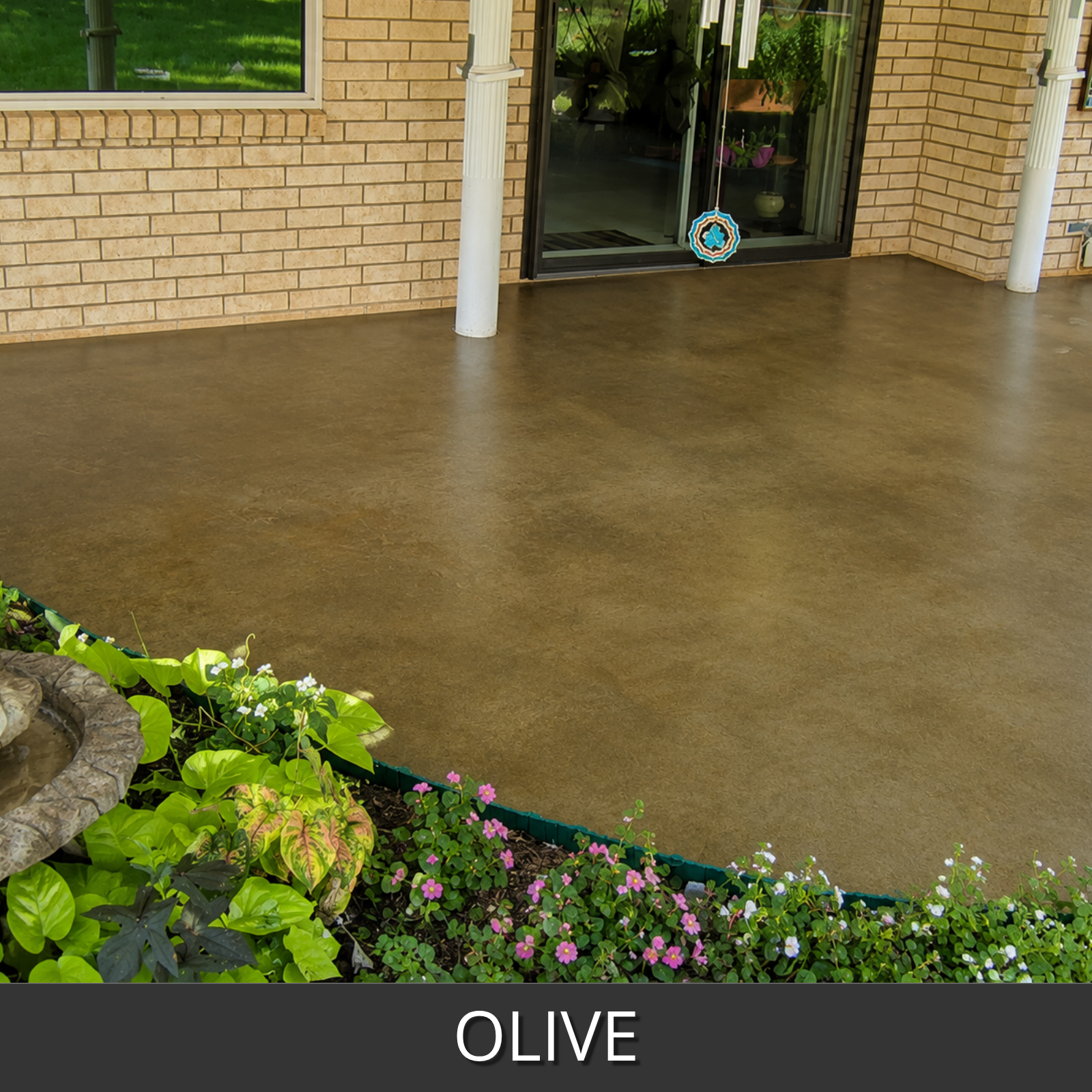 A patio floor in an olive concrete finish, shown in front of a brick house with glass doors