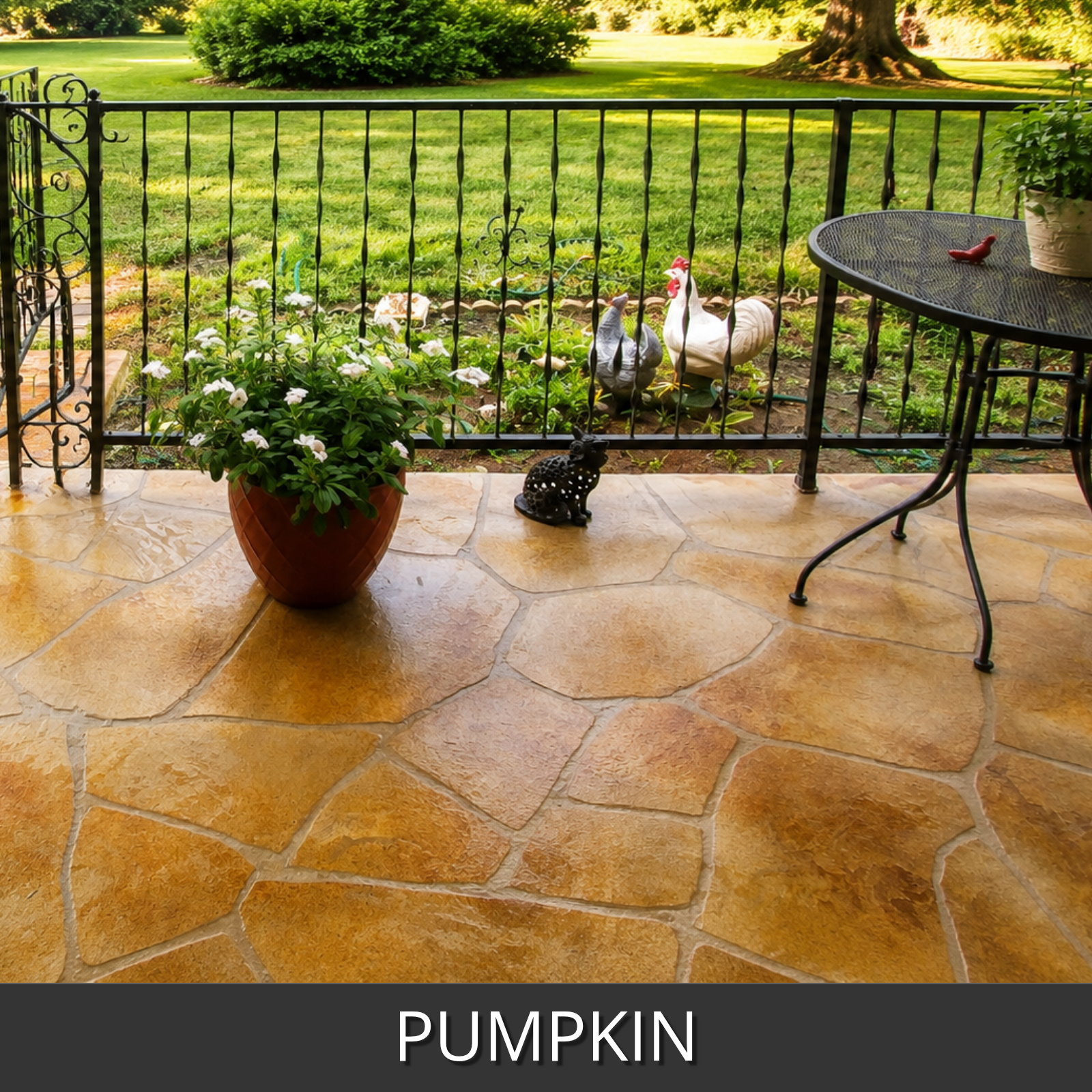 A faux flagstone patio design in a backyard with a black metal fence and a green lawn. The patio features irregular, warm pumpkin-toned stained faux flagstone concrete pavers.