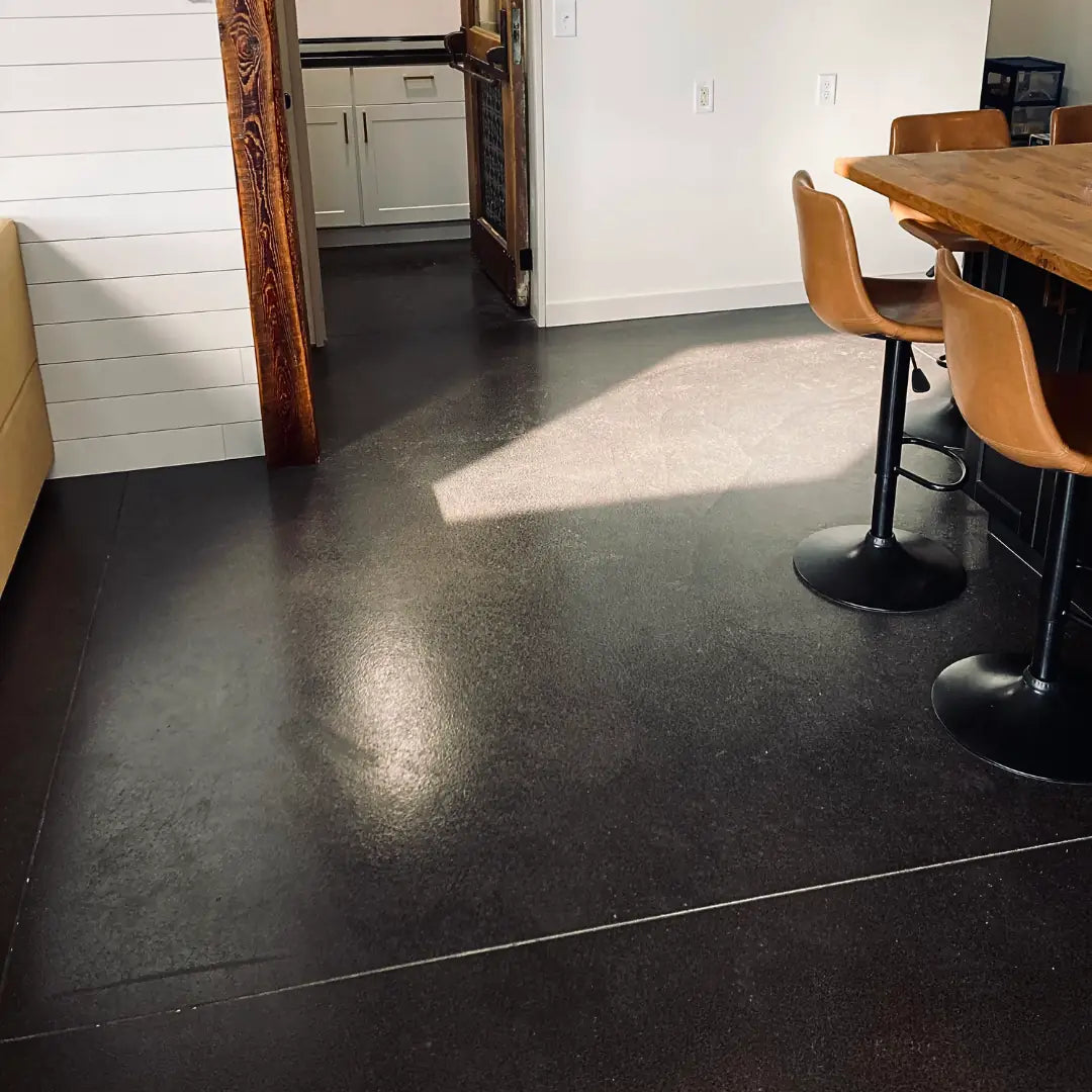 Modern kitchen with dark concrete flooring and wooden furniture.