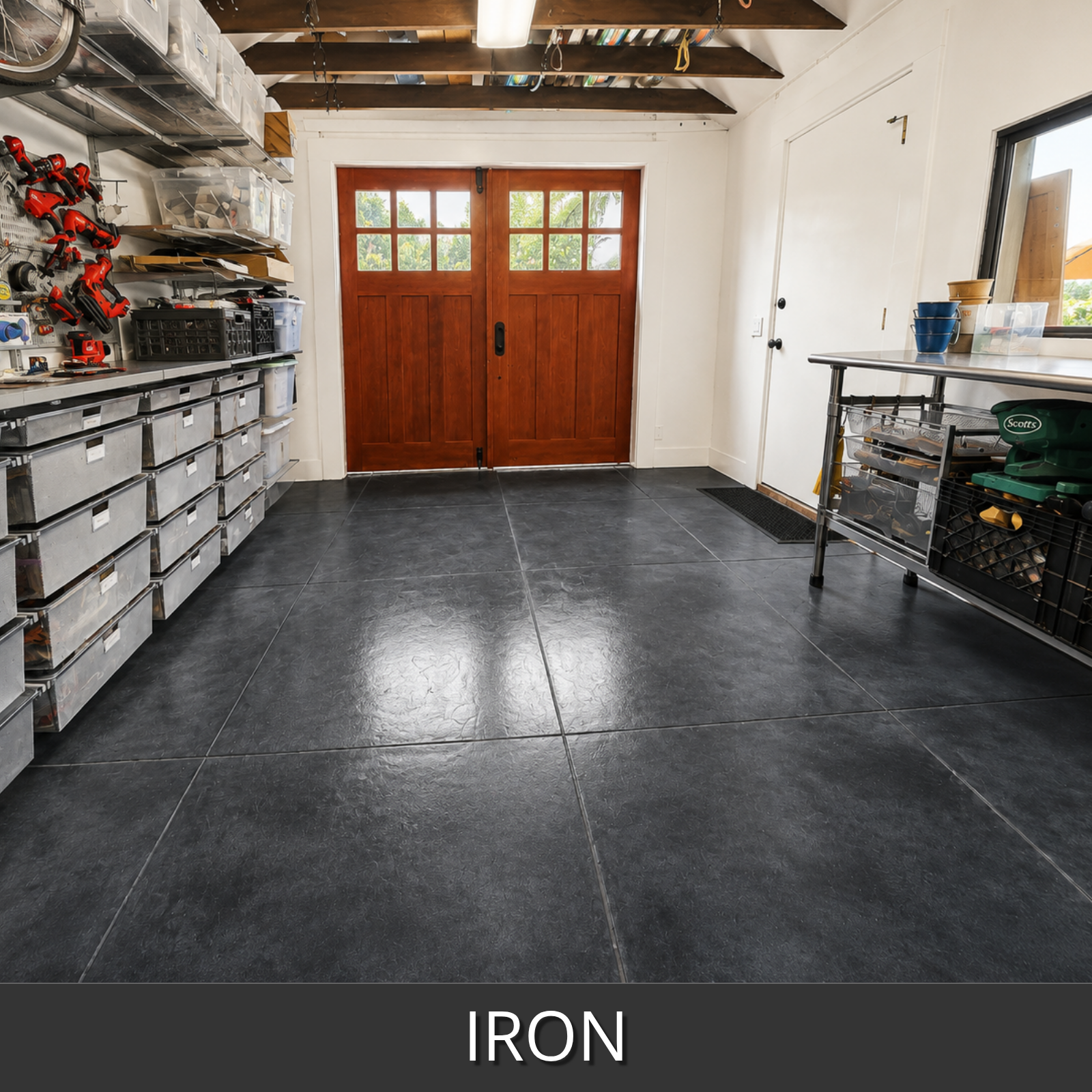 A large-format dark gray iron-look colorwave floor tile shown in a garage setting with a wooden double door, workbench, and storage drawers.