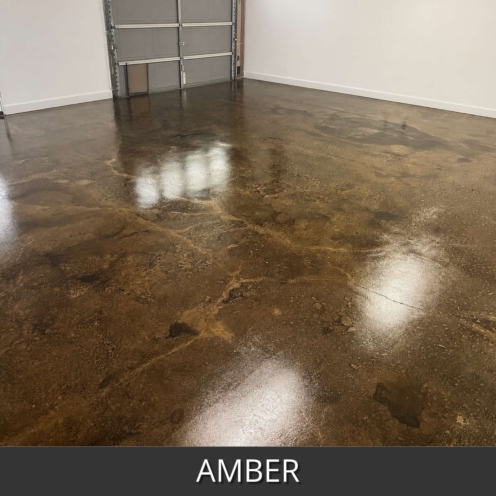 A glossy concrete floor in a garage-like room, shown in an amber colorwave stain finish. The floor has a mottled brown and tan marbled pattern with bright reflections from overhead lights.