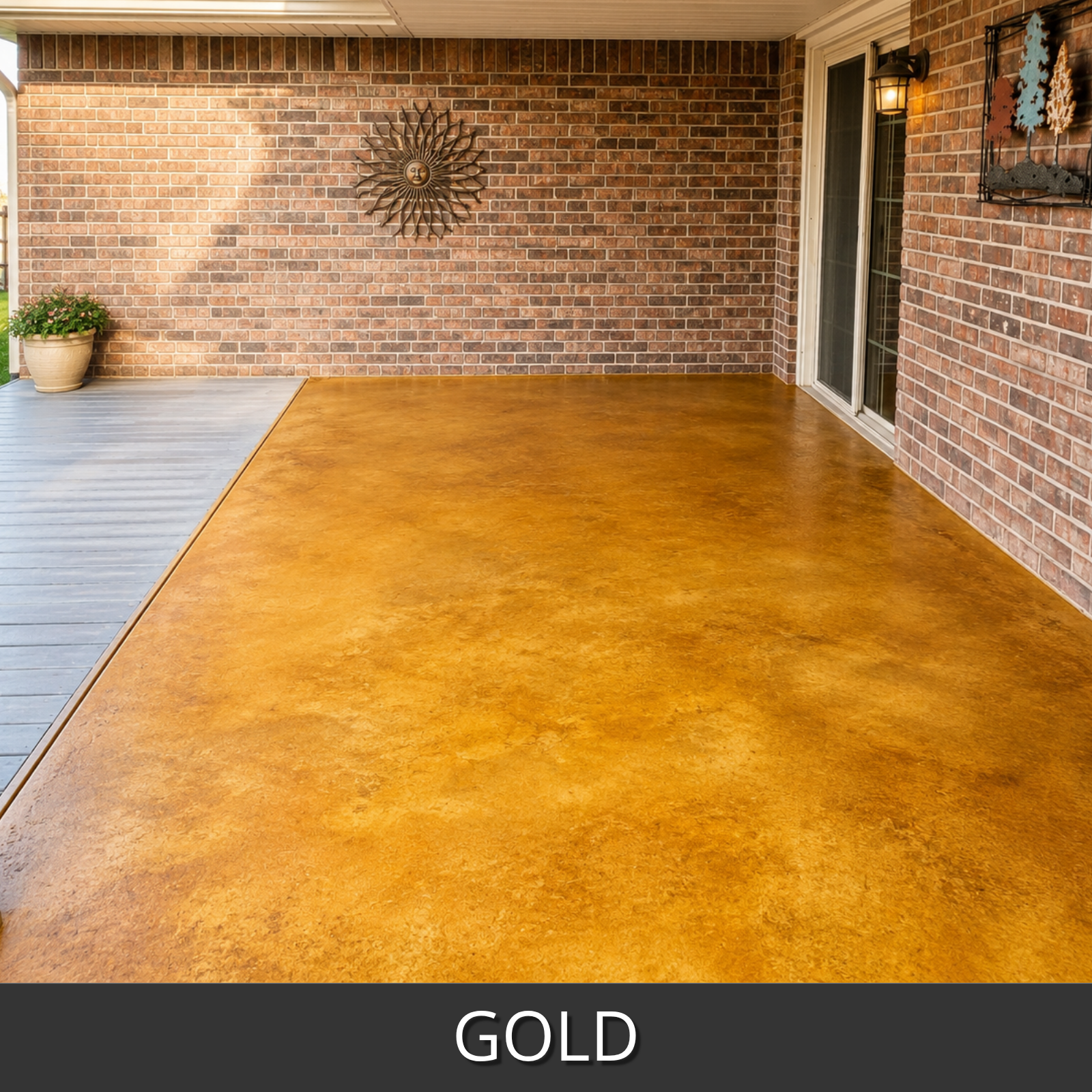 A large outdoor patio floor in gold colorwave stain, shown next to a gray deck and a brick wall with a sliding glass door.