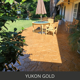 Stamped concrete patio with a table and umbrella beside a lawn, Antiquing™ Stamped Concrete Stain in 430 Yukon Gold