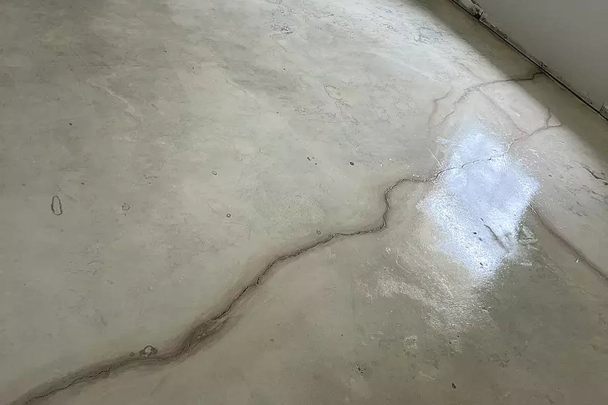 Close-up of a glossy concrete floor tinted with AcquaTint™ in Buff, with a crack running through the slab