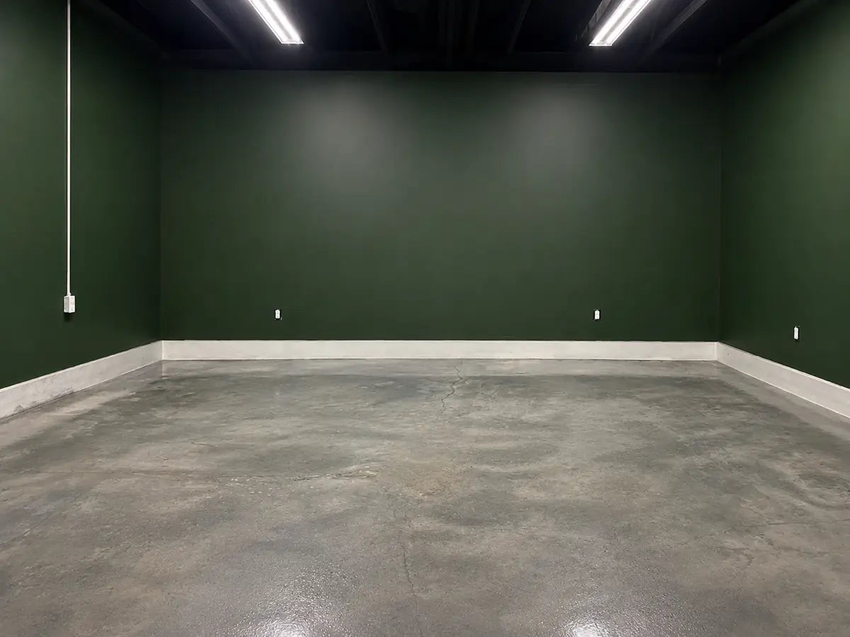 Dyed concrete floor in an empty room with a dark green wall, Vibrance™ Concrete Dye in Charcoal, Khaki and White