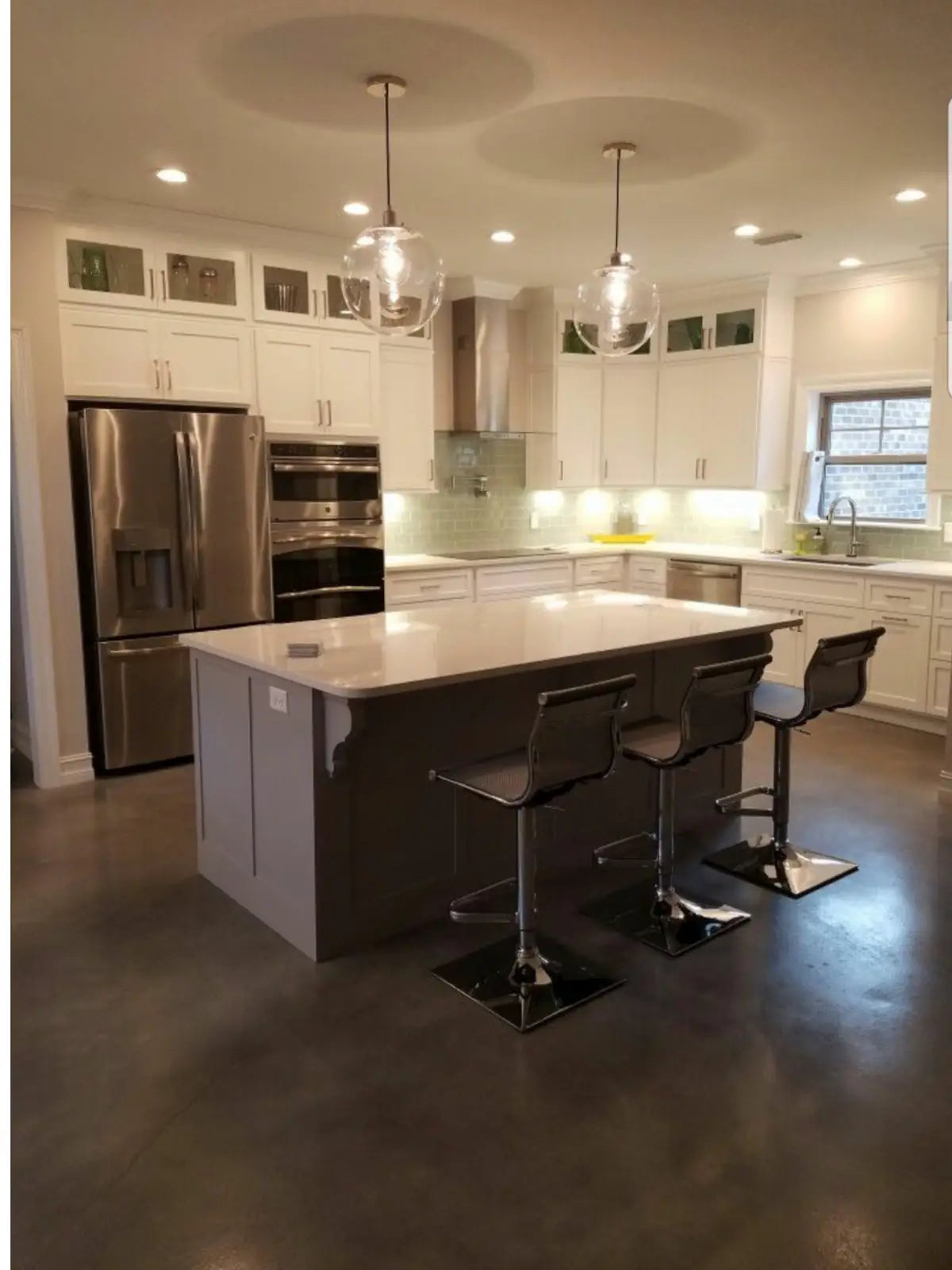 Stained and dyed concrete kitchen floor with a large island and bar stools, Vibrance™ Concrete Dye in Charcoal, Light Slate, Stormy Gray and White