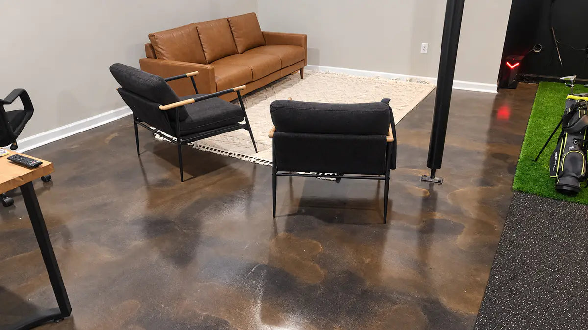 Dyed concrete floor in a finished basement lounge with a leather sofa, Vibrance™ Concrete Dye in Charcoal and Tweed