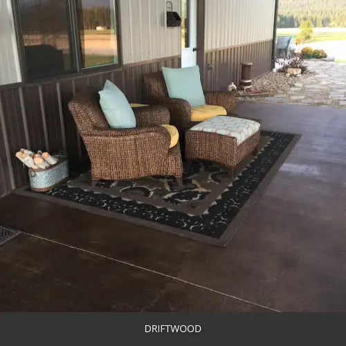 Stamped concrete patio with wicker chairs and a rug at a metal building, EasyTint™ Tinted Concrete Sealer in 511 Driftwood