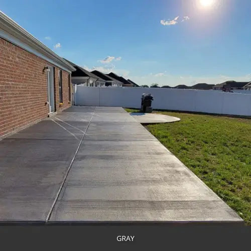Sealed concrete patio slab beside a brick house and a lawn, EasyTint™ Tinted Concrete Sealer in 515 Gray