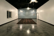 Tinted concrete floor in a large room with a dark rug, AcquaTint™ in 506 Charcoal finished with ProWax Polish™ Gloss