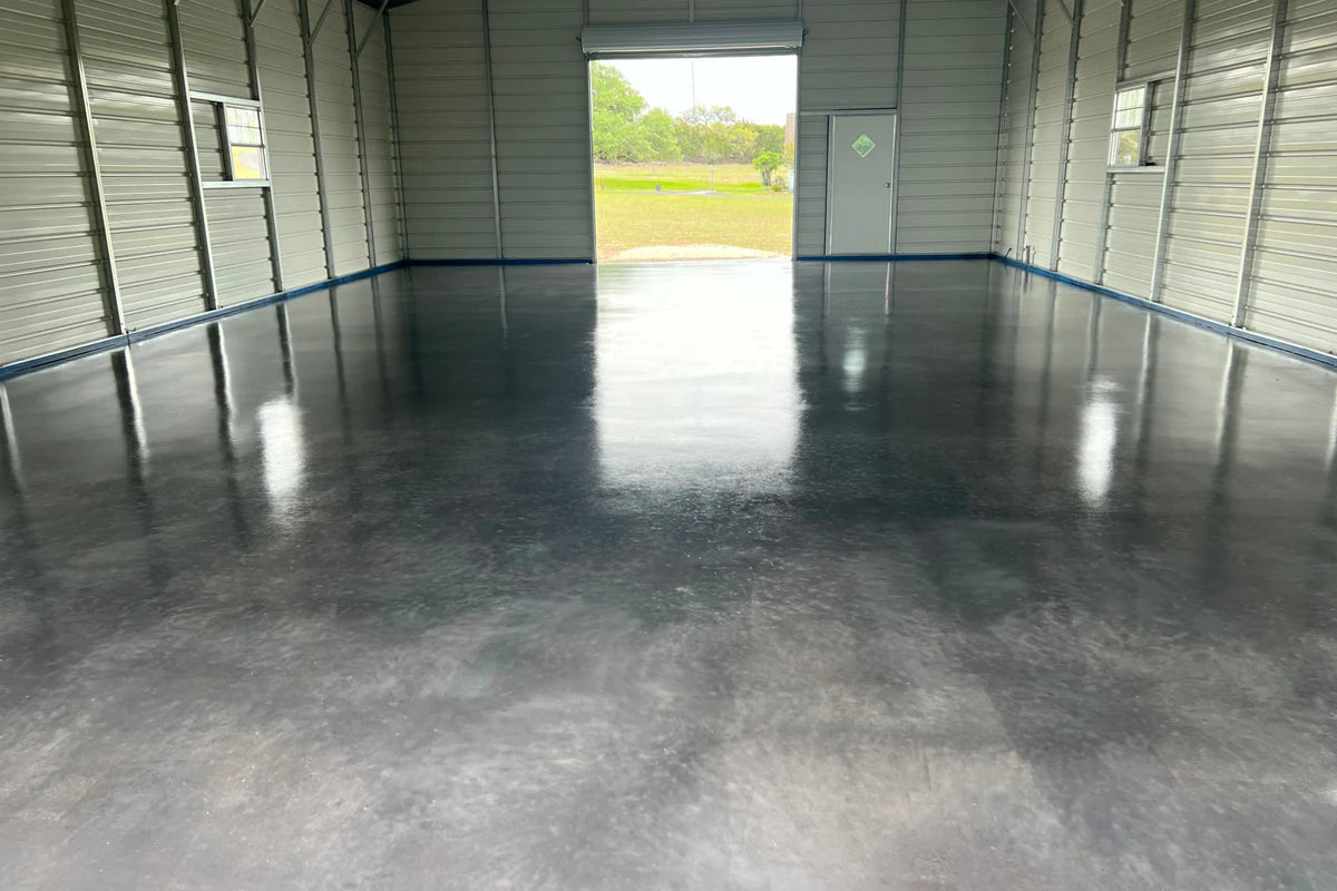 Tinted concrete floor in a metal barndominium shop with the roll-up door open, AcquaTint™ in 506 Charcoal finished with ProWax Polish™ Satin