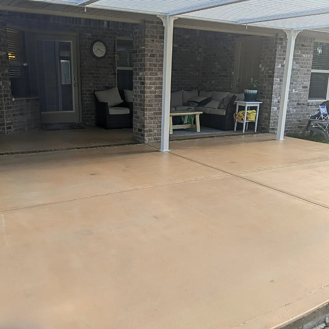 Covered patio with outdoor furniture and a clock on a brick wall.
