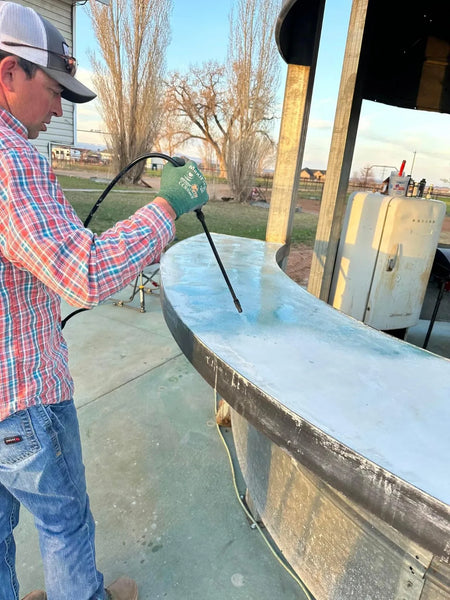 Homeowner spraying acid stain onto a round concrete grain-bin bar top