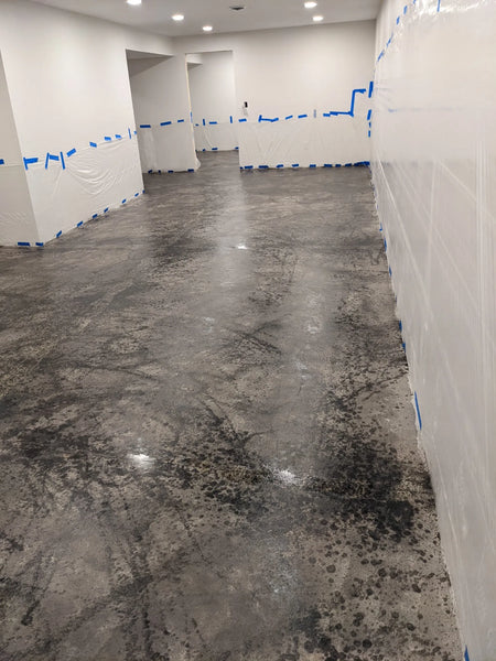 Used a roller to apply a lighter gray color over the splashed charcoal, creating a mottled, random look