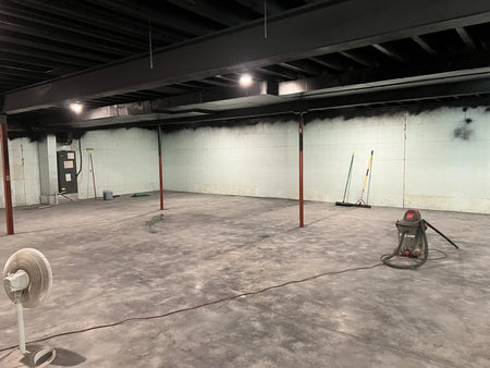 An image showing a concrete basement floor prepped for AquaTint application, having undergone power washing, stripping, and sanding