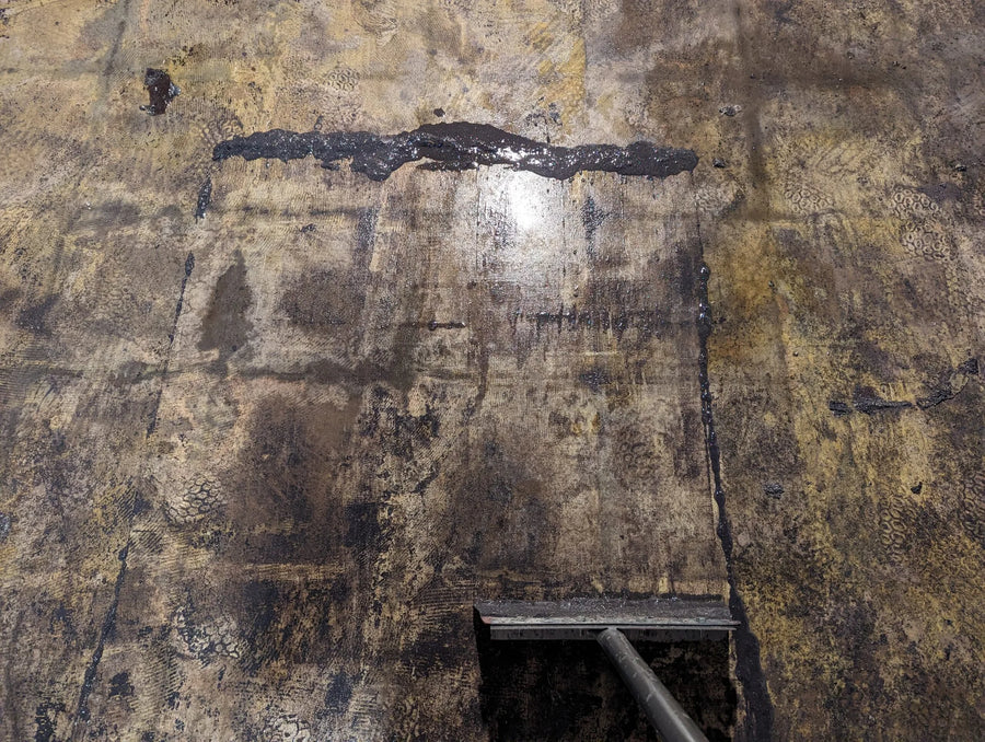 Photograph showing the process of mastic removal from the basement floor using Bean E Doo and a trowel