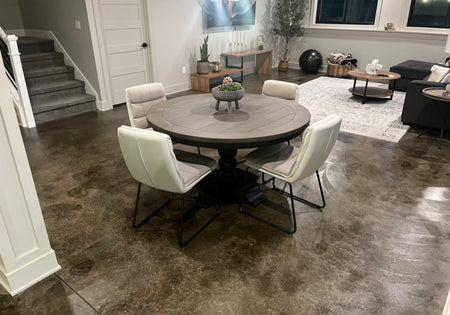 A finished basement living and dining area with a ColorWave Molasses stained concrete flor, modern furnishings, and soft lighting
