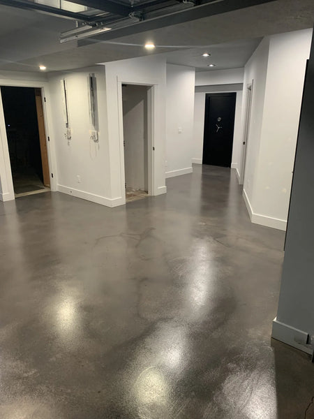 A basement hallway with a faux polished concrete floor, featuring smooth, reflective surfaces and light-colored walls