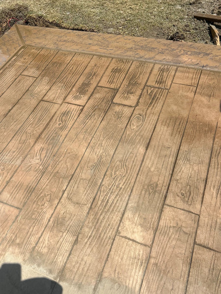 Integrally pigmented concrete overlay stamped with a wood-plank pattern, ready to stain