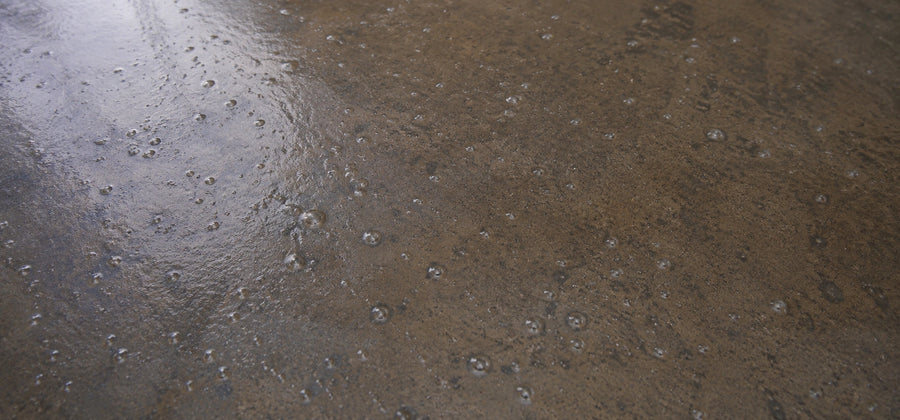 Bubbles, blisters, and pinholes visible in a cured concrete sealer film caused by trapped moisture vapor or coats applied too thick