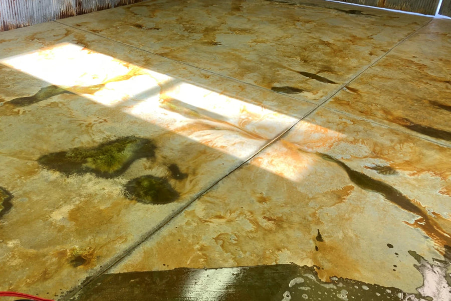 Chalky white acid stain residue on a brown stained concrete floor that must be rinsed and vacuumed off before sealing