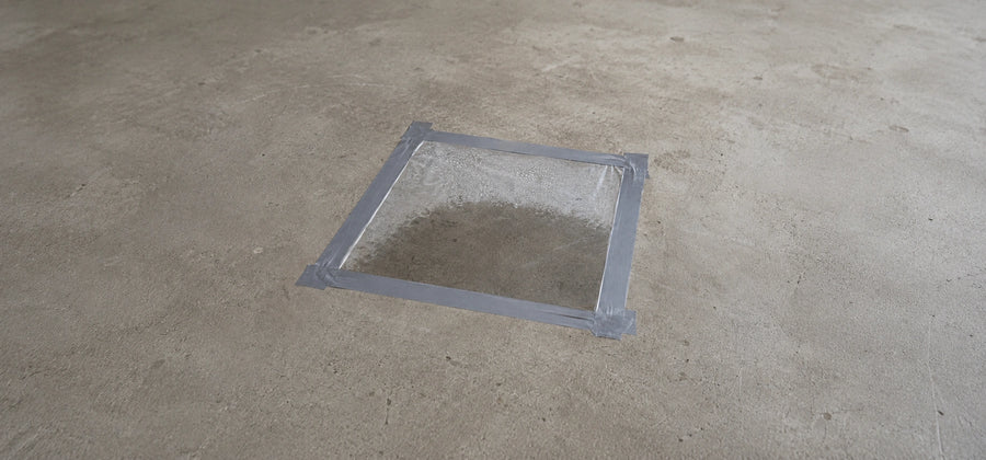 Clear plastic sheet taped flat to a concrete floor with duct tape on all four edges to perform the 24 to 48 hour slab moisture test before sealing