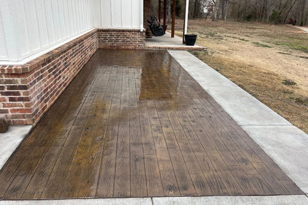 Color hardener broadcast over a Tobacco-pigmented slab before wood-plank stamping