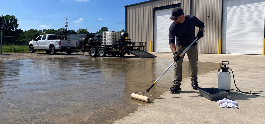 Contractor rolling concrete sealer onto a commercial driveway, keeping a wet edge