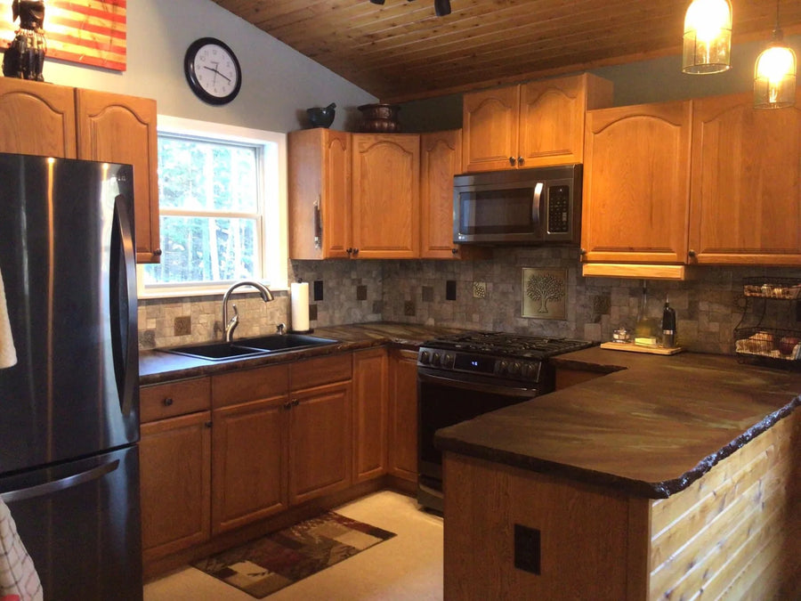 Installed kitchen concrete countertop featuring a mottled rustic look achieved through acid staining with Coffee Brown, Seagrass, and Desert Amber colors using wet-on-wet technique
