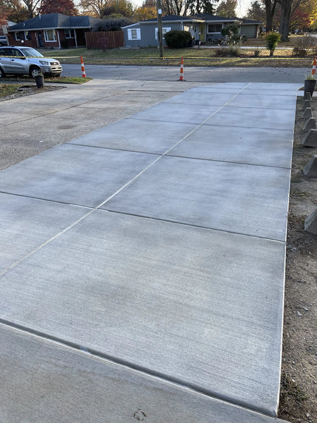 Unstained broomed concrete driveway in its original light grey color before the application of the stain