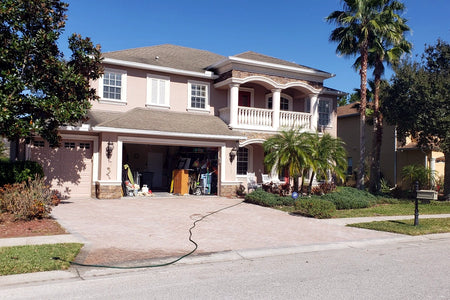 Front of a two-story home with a faded concrete driveway before a Milano Red and Charcoal color update