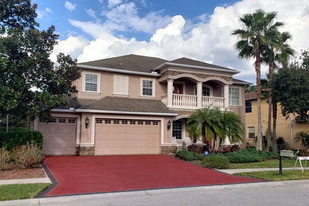 Two-story home with a Milano Red concrete driveway and Charcoal border after refinishing