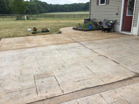 A sun-faded, stamped concrete driveway with a worn-out compass rose imprint