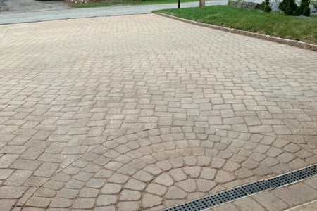 Faded paver-style concrete driveway before staining with dull light concrete color and worn surface tone