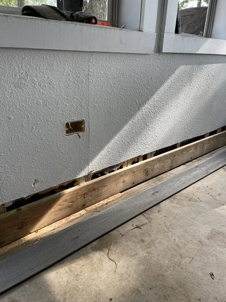 Pre-transformation sunroom floor with evident wear and tear, including stains from dirt, rust, paint, and drywall mud