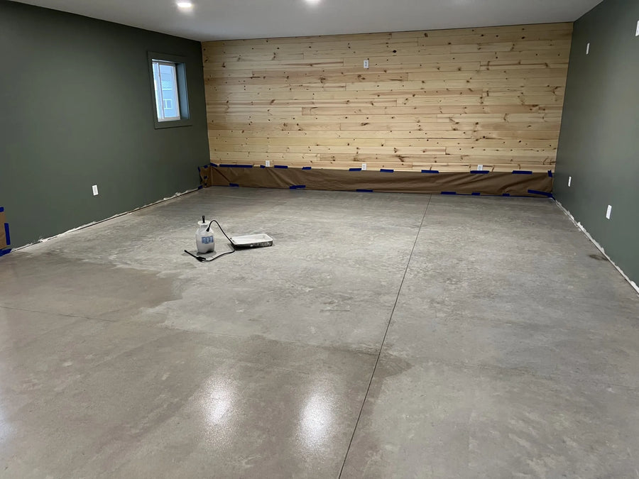 Concrete floor prepped for staining in a barn living space with a pump sprayer