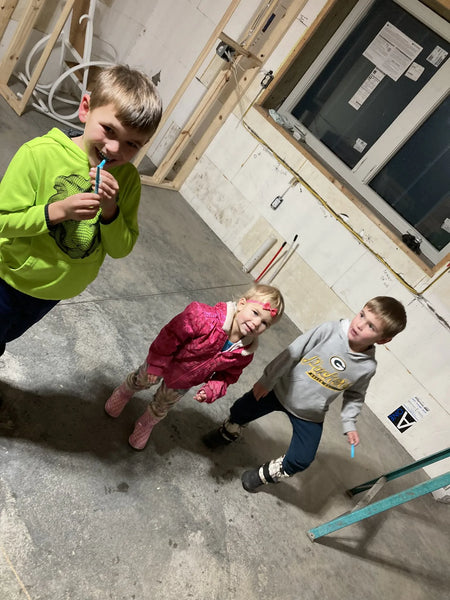 Three playful children having fun on an untreated concrete floor, showing its raw state prior to staining