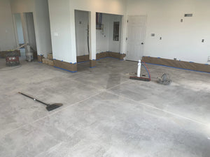 Freshly ground concrete floor of a cabin with a broom laid across, indicating recent cleaning