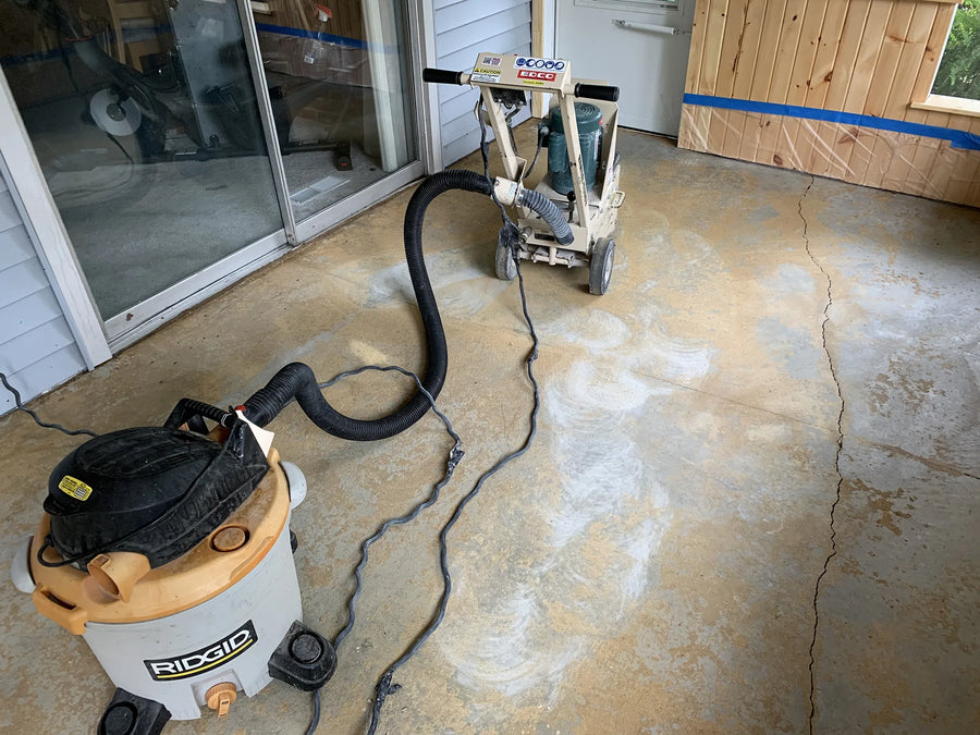 Concrete floor with carpet removed, in the process of grinding the stubborn carpet glue with a machine