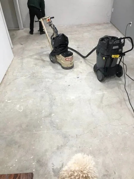 Concrete surface preparation: Concrete floor with paint drips and glue, plus grinder and vacuum for cleanup