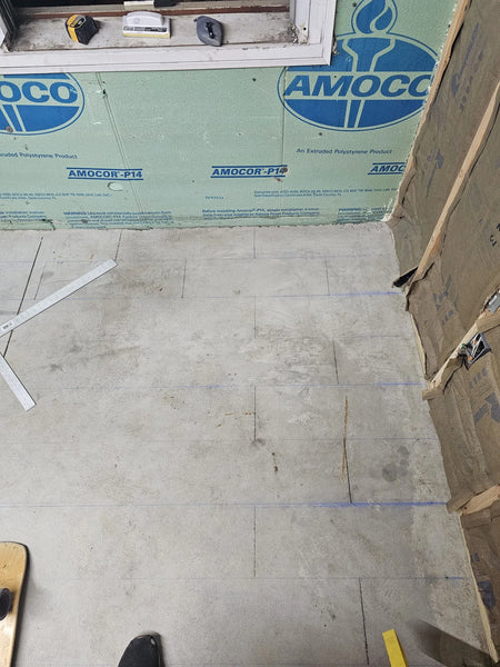 A chalk line being used to map out the future tile design on the concrete floor