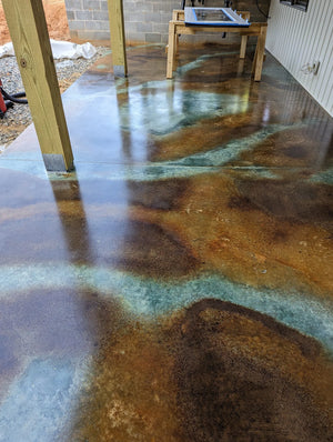 Concrete floor featuring a marbled design with freehand vein patterns using EverStain Coffee, Malayan Buff, and Seagrass acid stains, sealed with a glossy finish