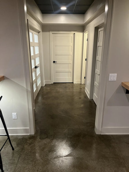 A modern entryway featuring a dark brown concrete floor stained with ColorWave Molasses, complementing contemporary decor