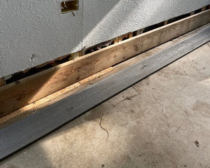 Pre-transformation sunroom floor with evident wear and tear, including stains from dirt, rust, paint, and drywall mud